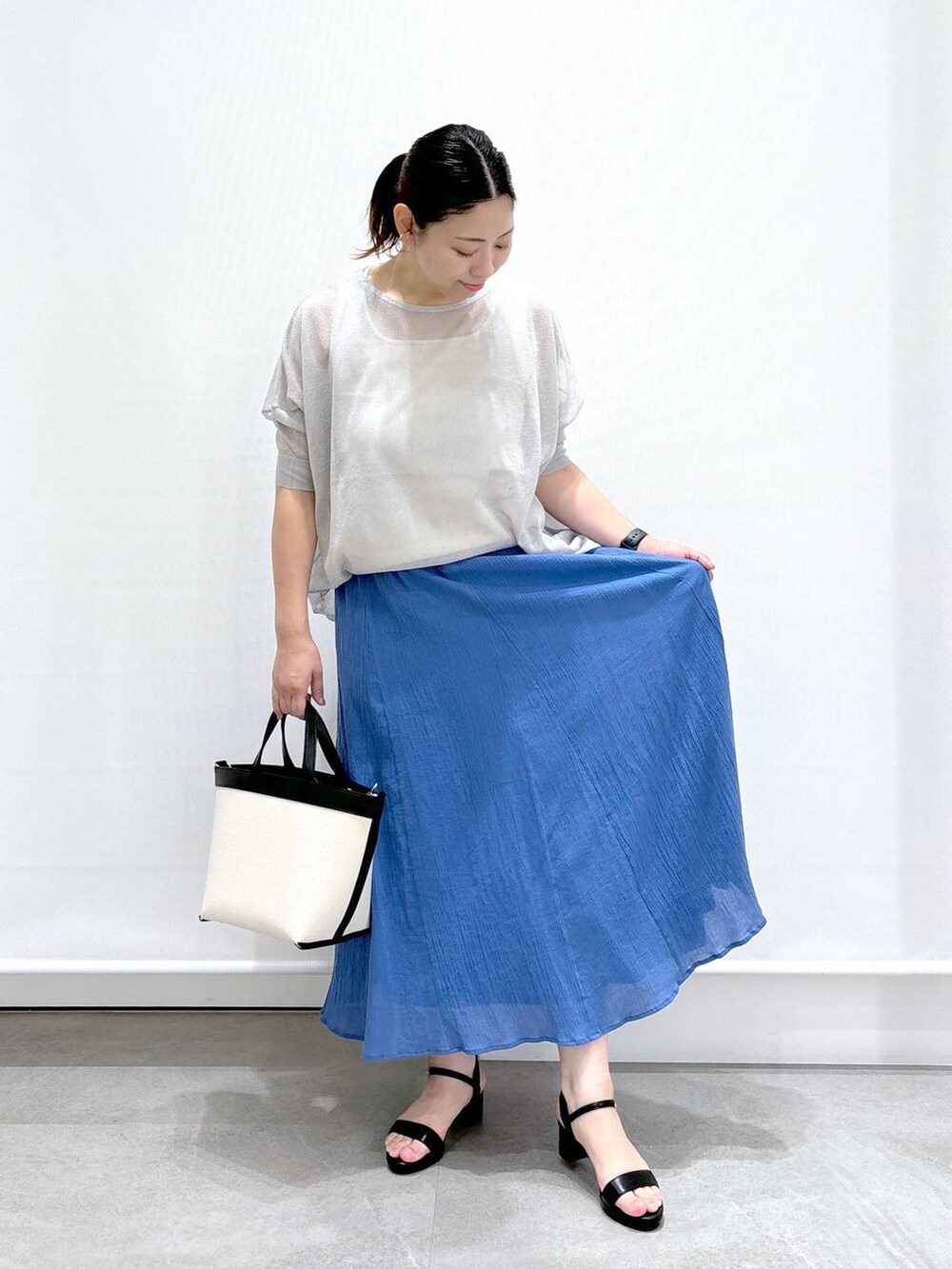 ブラック系のトートバッグ、グレー系のニット/セーター、ホワイト系のタンクトップを着用したレディースの夏コーディネートの2枚目の写真