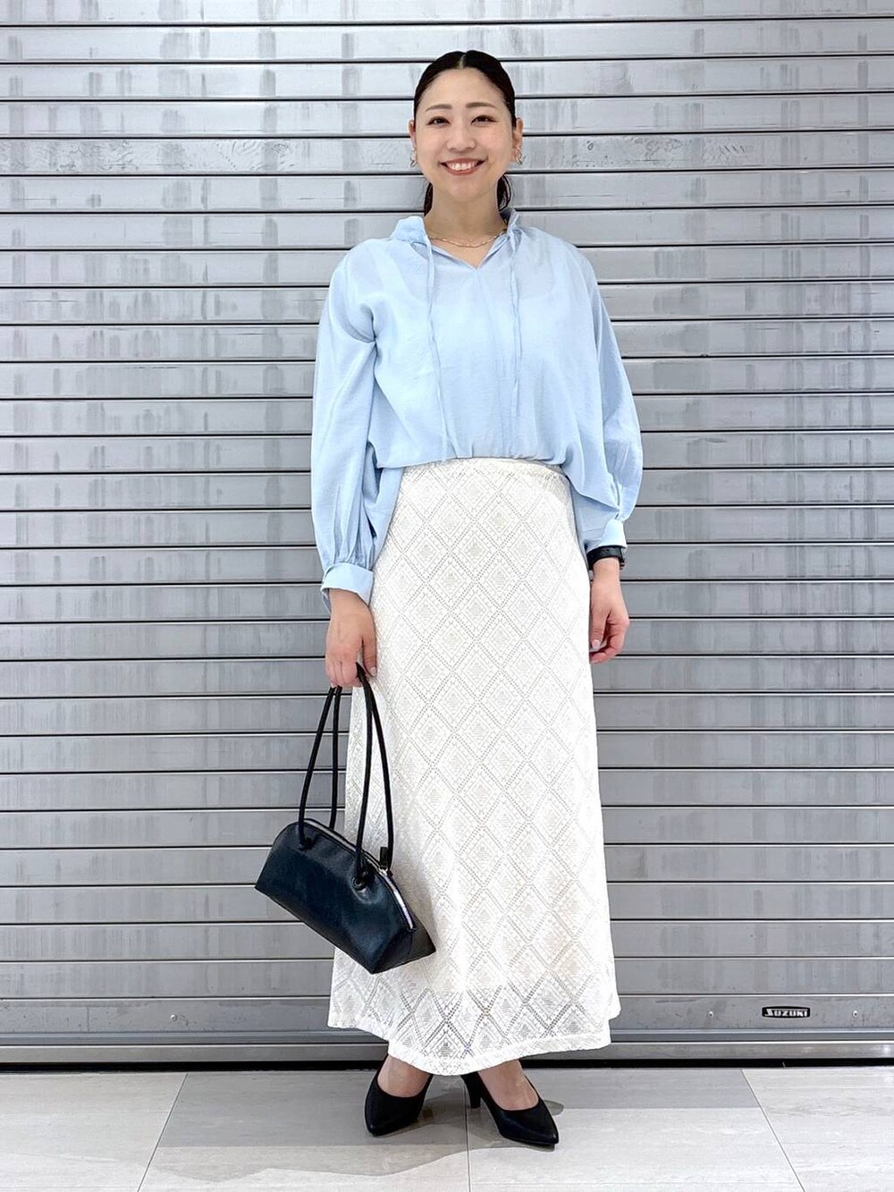 ブラック系のパンプス、ブラック系のハンドバッグ、ブルー系のシャツ/ブラウスを着用したレディースの春コーディネートの2枚目の写真