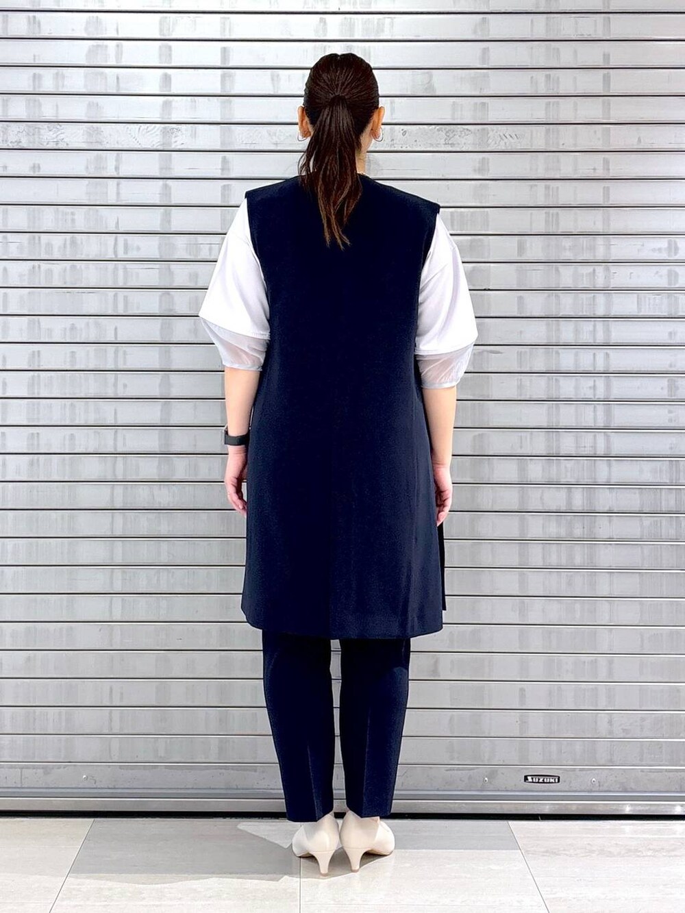 ホワイト系のパンプス、ベージュ系のハンドバッグ、ブルー系のその他パンツを着用したレディースの春コーディネートの4枚目の写真