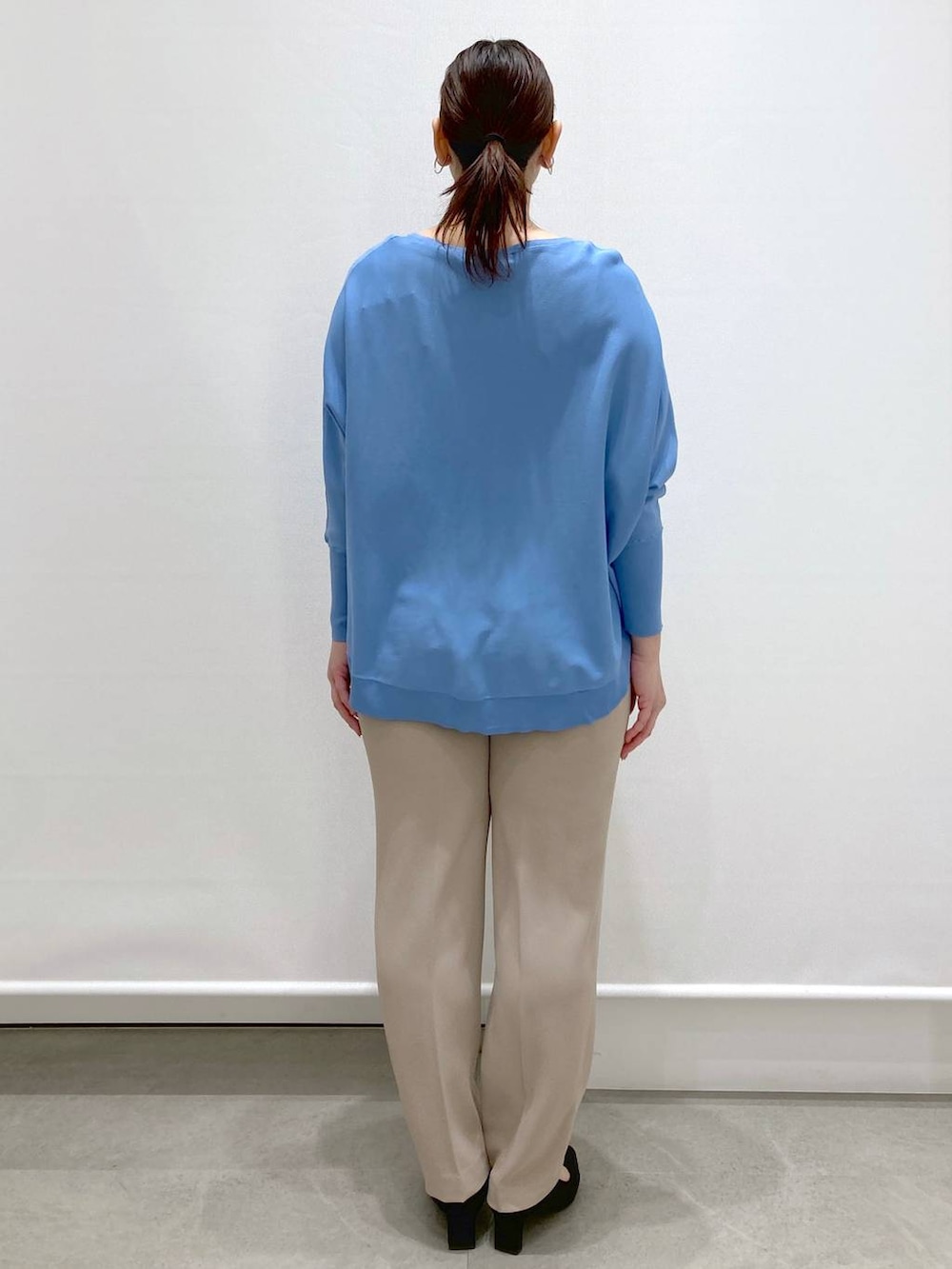 ブラック系のショルダーバッグ、ブルー系のニット/セーター、ベージュ系のその他パンツを着用したレディースの春コーディネートの4枚目の写真