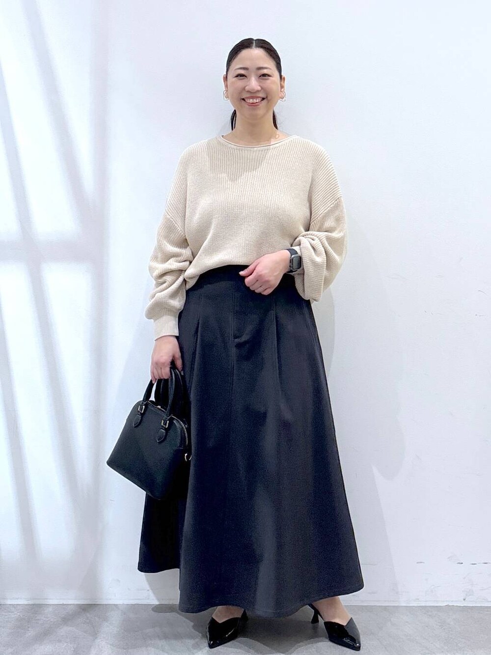 ホワイト系のニット/セーター、グレー系のスカートを着用したレディースの春コーディネートの2枚目の写真