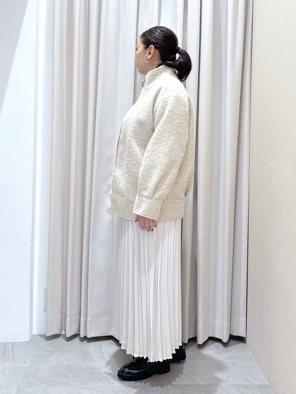 ブラック系のパンプス、ホワイト系のニット/セーター、ホワイト系のスカートを着用したレディースの秋コーディネートの3枚目の写真