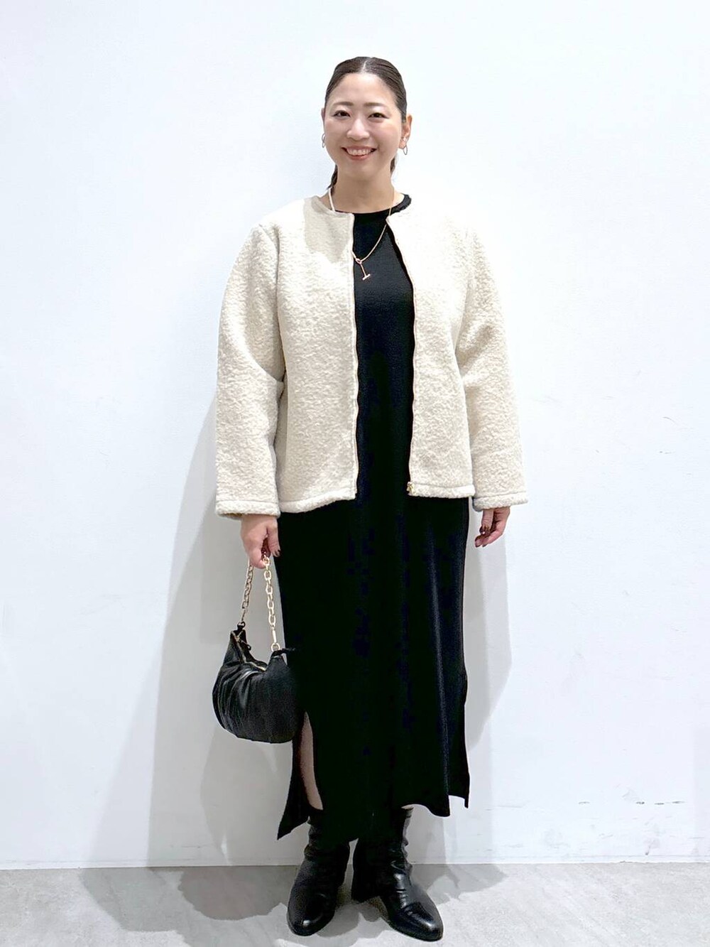 ベージュ系のノーカラージャケット、ブラック系のブーツ、ブラック系のワンピースを着用したレディースの秋コーディネートの2枚目の写真
