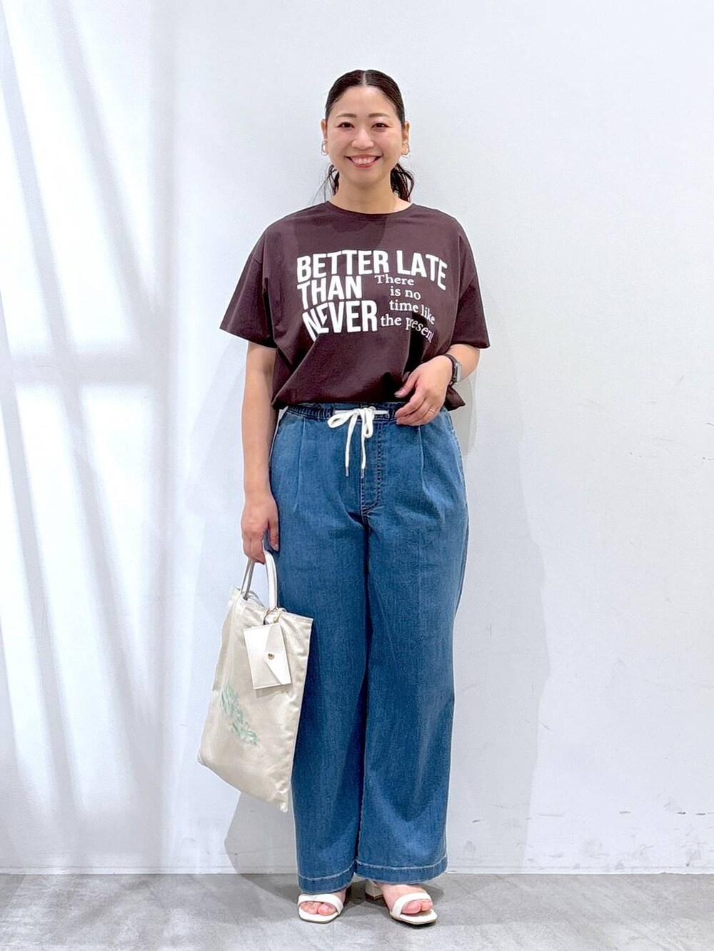 ホワイト系のトートバッグ、ブルー系のデニムパンツ、ブラウン系のTシャツ/カットソーを着用したレディースの夏コーディネートの2枚目の写真