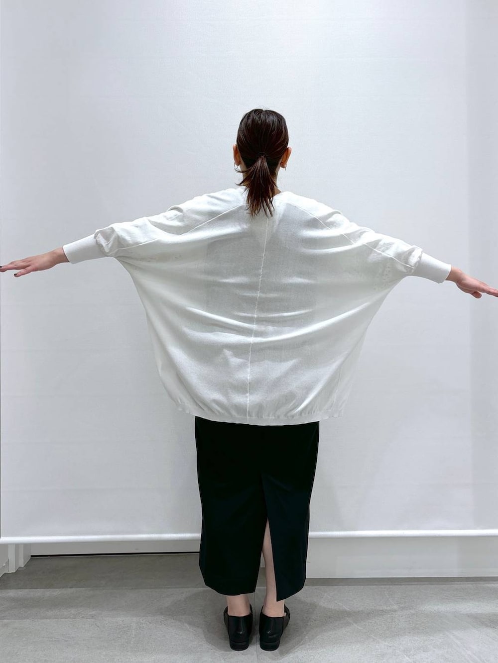 イエロー系のシャツ/ブラウス、ホワイト系のカーディガン/ボレロ、ブラック系のジャンパースカートを着用したレディースの春コーディネートの6枚目の写真