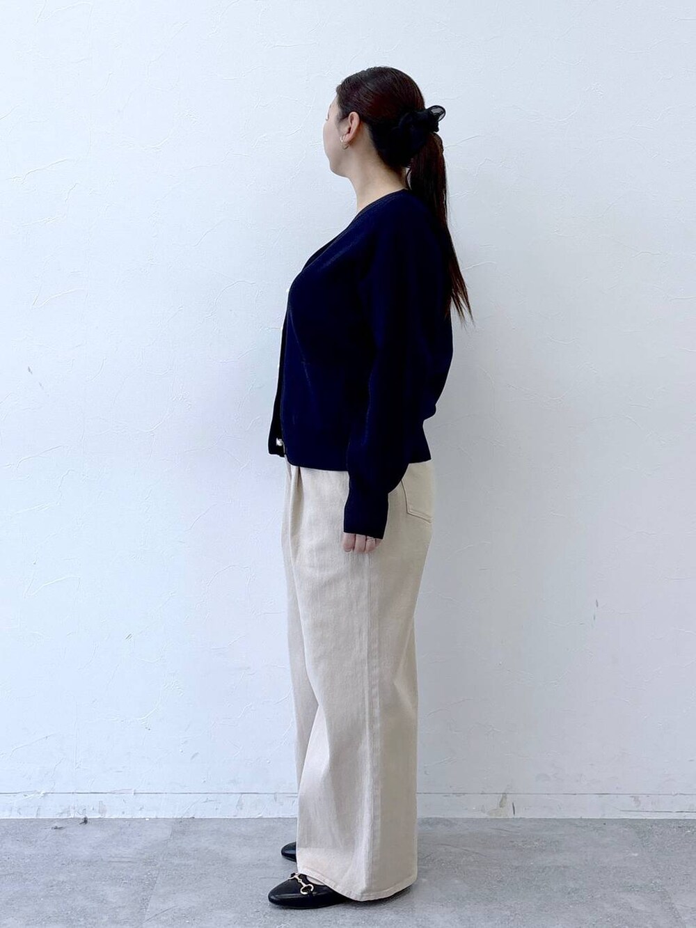 ブラック系のハンドバッグ、ベージュ系のデニムパンツ、ブラック系のパンプスを着用したレディースの冬コーディネートの3枚目の写真