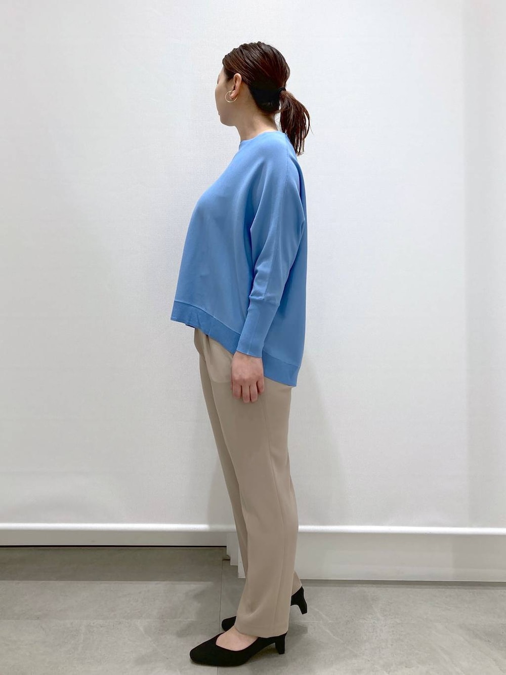 ブラック系のショルダーバッグ、ブルー系のニット/セーター、ベージュ系のその他パンツを着用したレディースの春コーディネートの3枚目の写真