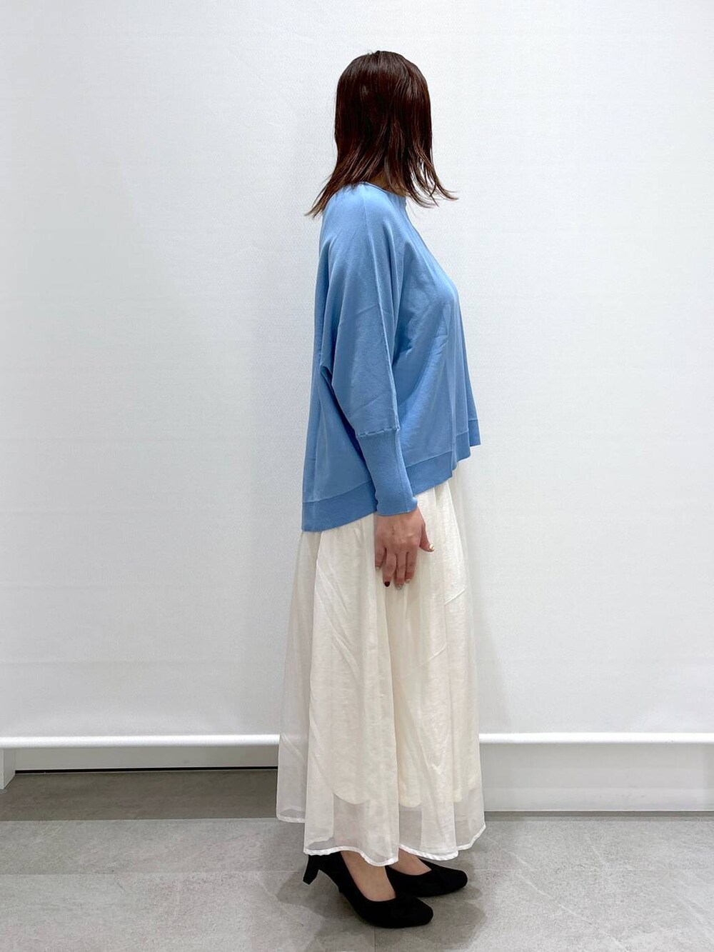 ホワイト系のスカート、ブラック系のショルダーバッグ、ブラック系のパンプスを着用したレディースの春コーディネートの5枚目の写真