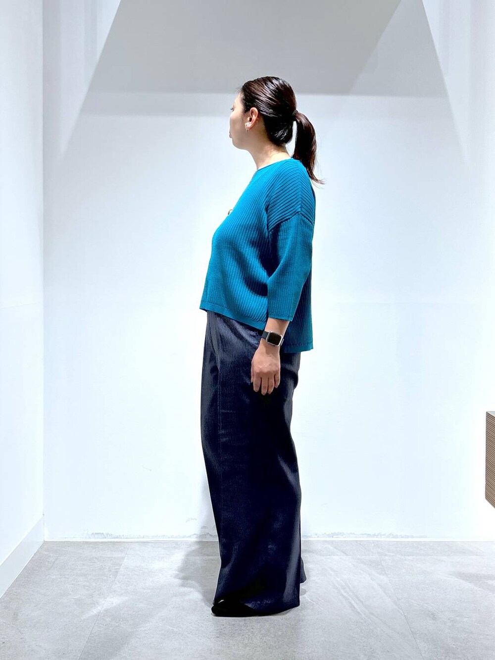 ブルー系のニット/セーター、ブラック系のパンプス、ブルー系のデニムパンツを着用したレディースの秋コーディネートの3枚目の写真