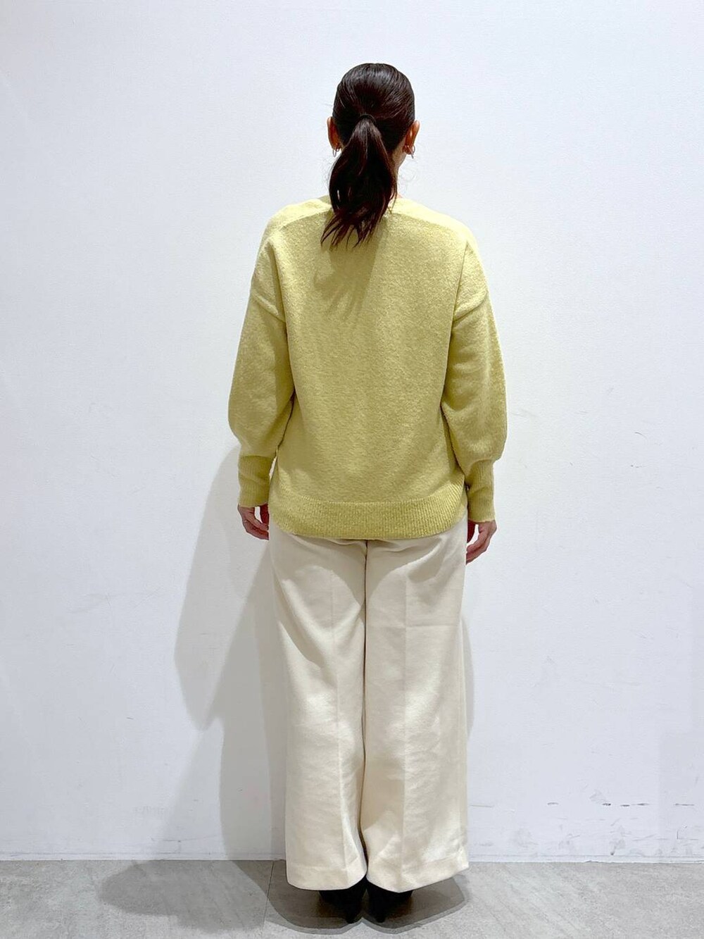 ブラック系のトートバッグ、イエロー系のニット/セーター、ホワイト系のその他パンツを着用したレディースの冬コーディネートの4枚目の写真