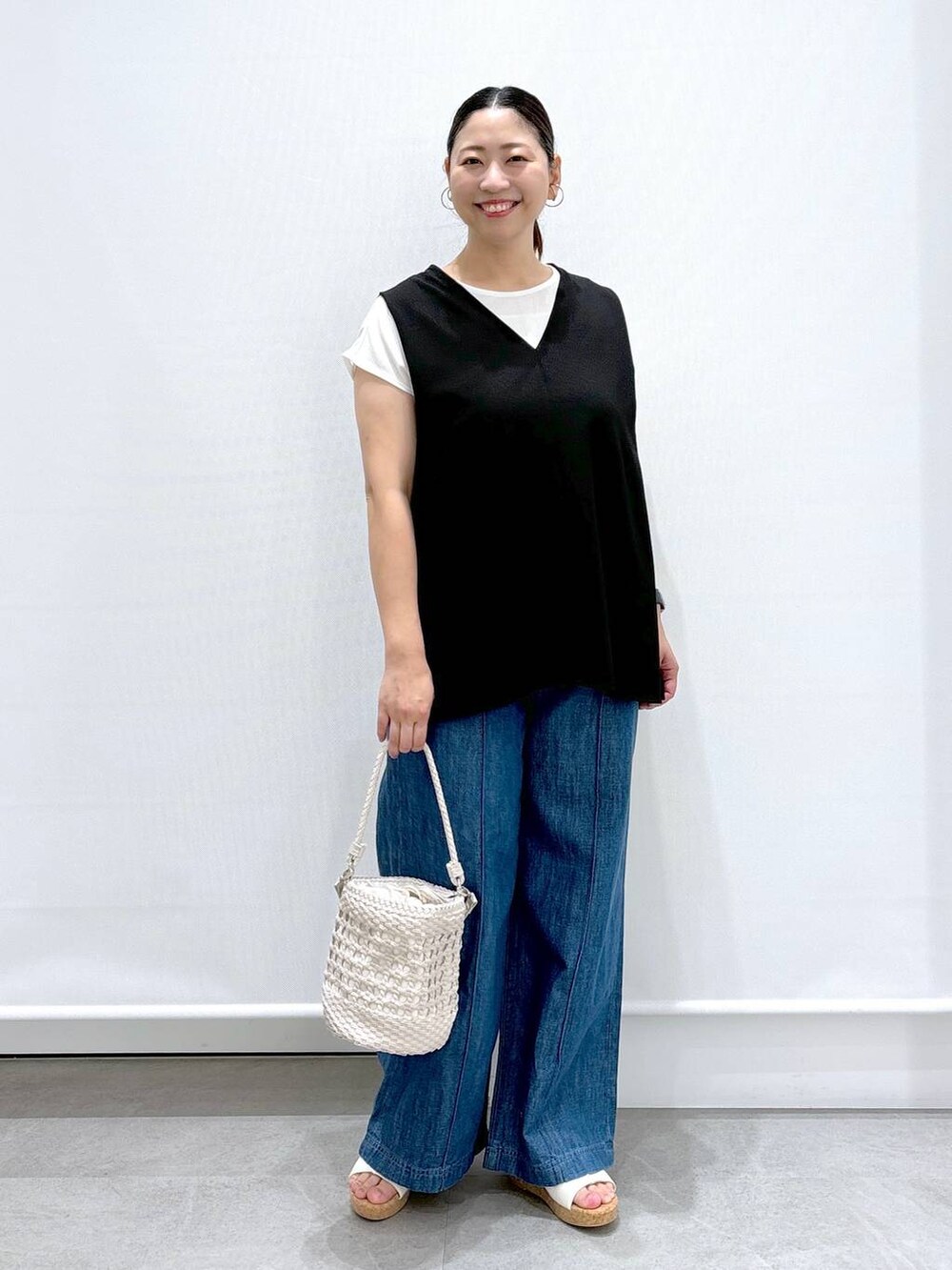 ブルー系のデニムパンツ、ブラック系のシャツ/ブラウス、ホワイト系のサンダルを着用したレディースの夏コーディネートの2枚目の写真