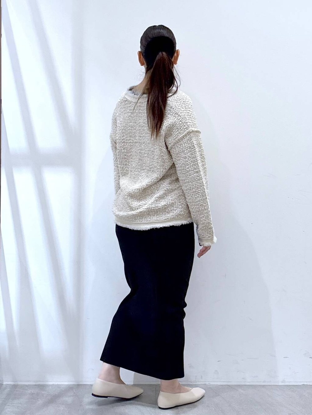 ベージュ系のスカート、ホワイト系のパンプス、ホワイト系のトートバッグを着用したレディースの冬コーディネートの5枚目の写真