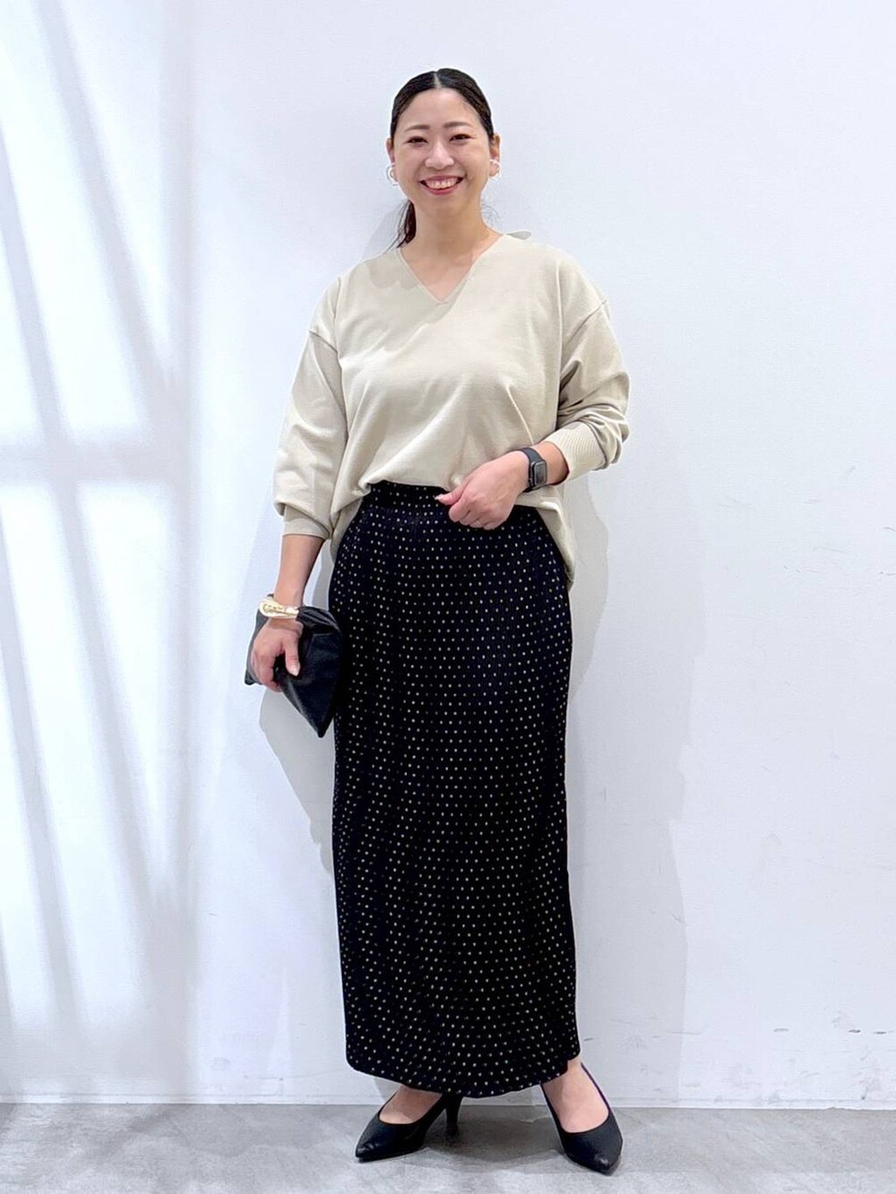 ブラック系のパンプス、ベージュ系のニット/セーター、ブラック系のスカートを着用したレディースの秋コーディネートの2枚目の写真