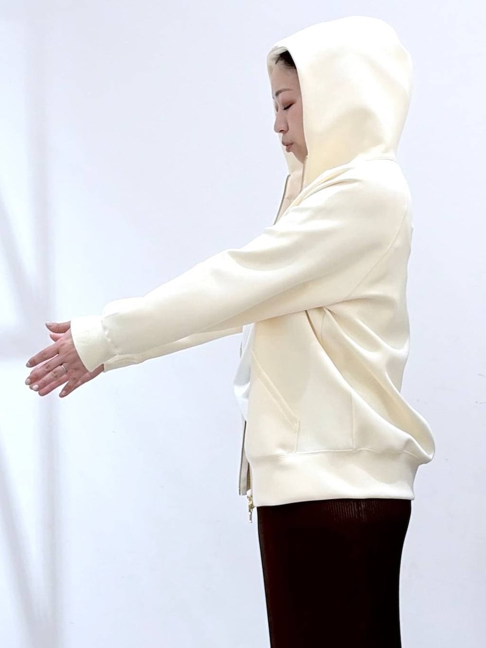 ホワイト系のパーカー、ブラウン系のスカート、ブラック系のショルダーバッグを着用したレディースの春コーディネートの6枚目の写真