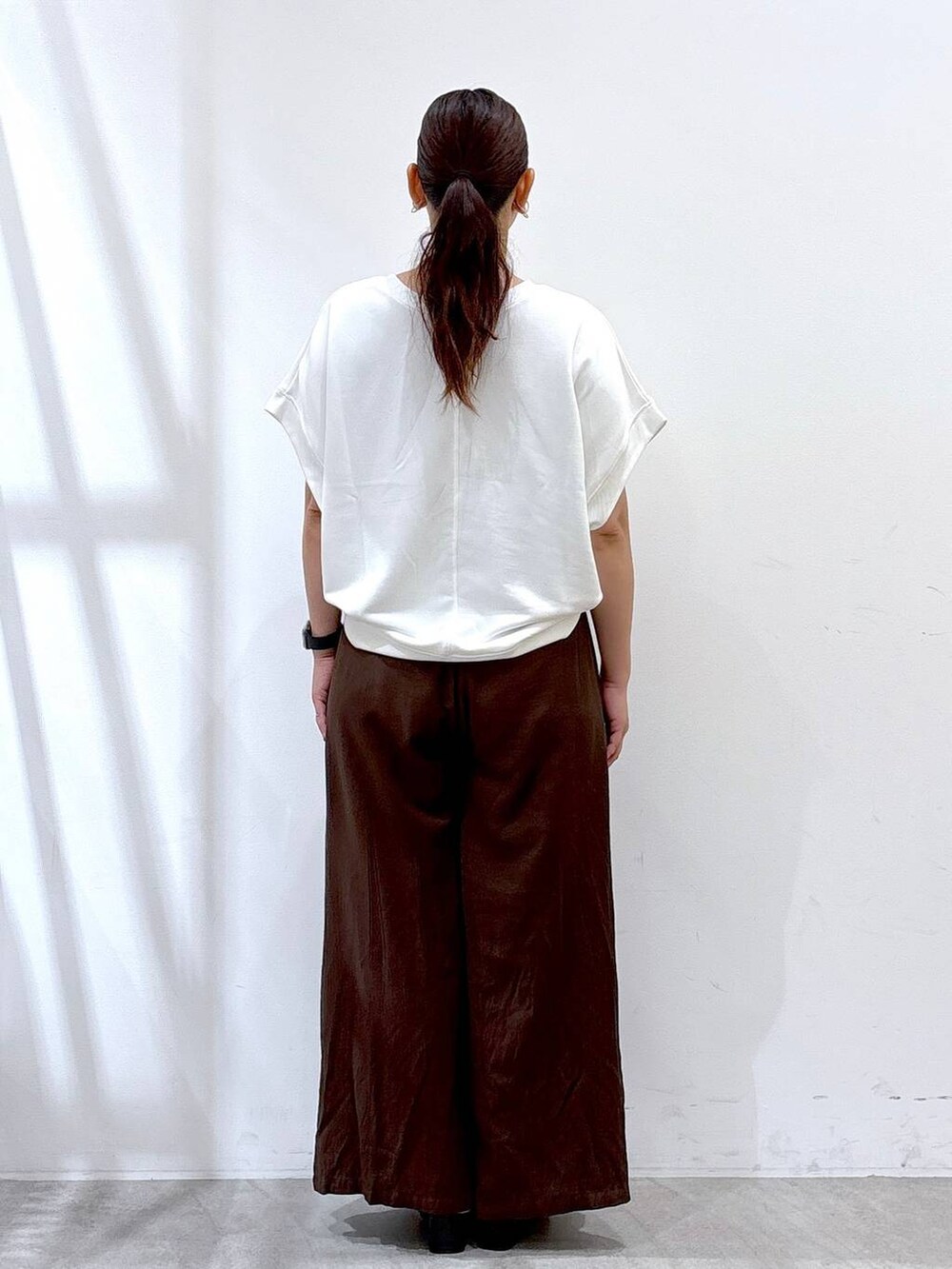 ブラウン系のその他パンツ、ブラック系のサンダル、ホワイト系のTシャツ/カットソーを着用したレディースの夏コーディネートの4枚目の写真