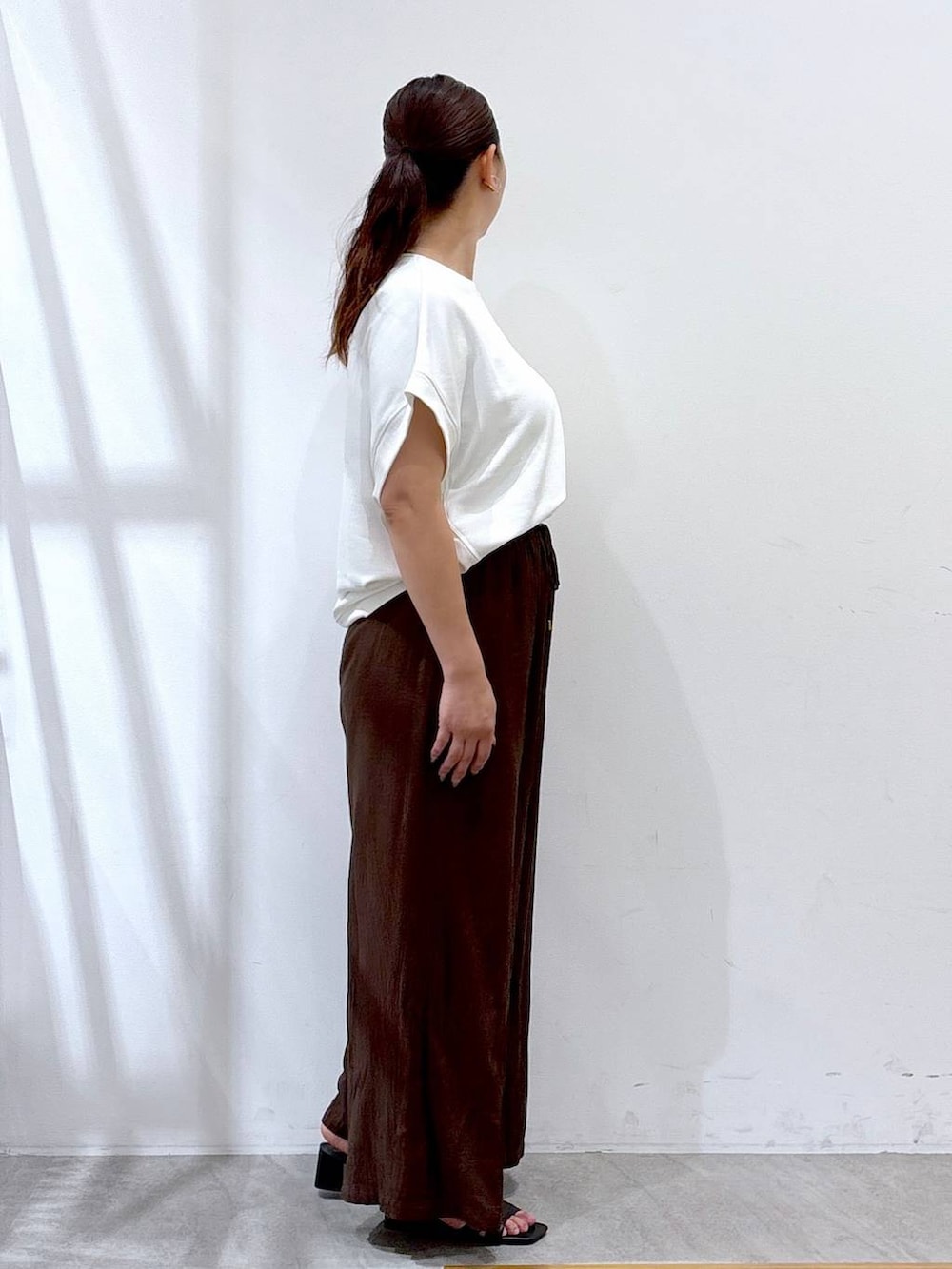 ブラウン系のその他パンツ、ブラック系のサンダル、ホワイト系のTシャツ/カットソーを着用したレディースの夏コーディネートの5枚目の写真