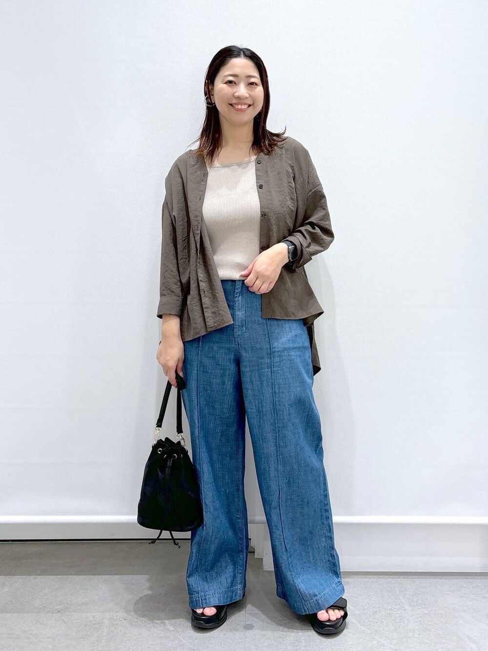 ブルー系のデニムパンツ、ブラック系のサンダル、ブラック系のハンドバッグを着用したレディースの夏コーディネートの2枚目の写真