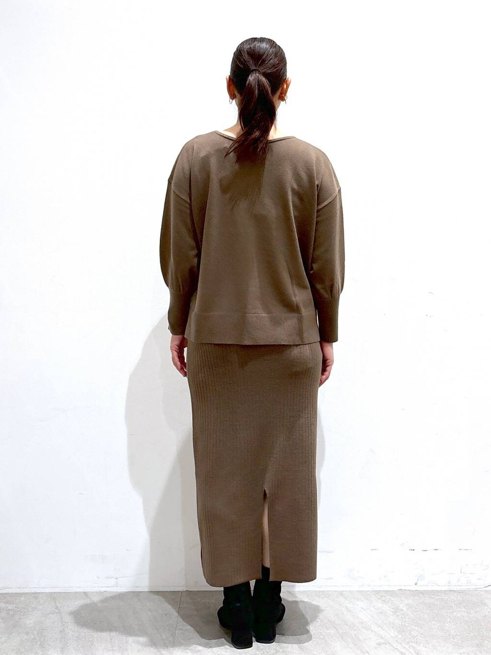 グレー系のブーツ、ブラック系のハンドバッグ、ホワイト系のその他アウターを着用したレディースの冬コーディネートの4枚目の写真