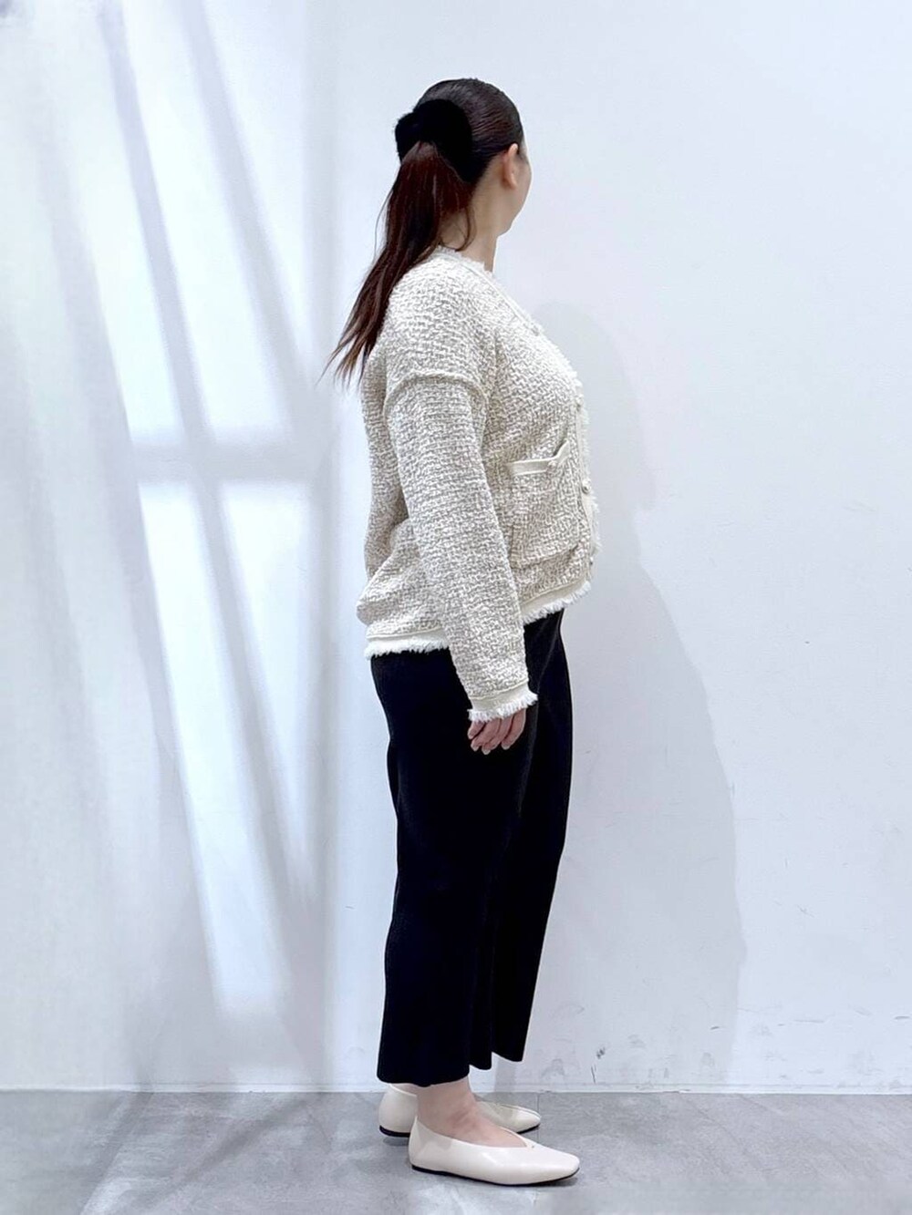 ベージュ系のスカート、ホワイト系のパンプス、ホワイト系のトートバッグを着用したレディースの冬コーディネートの6枚目の写真