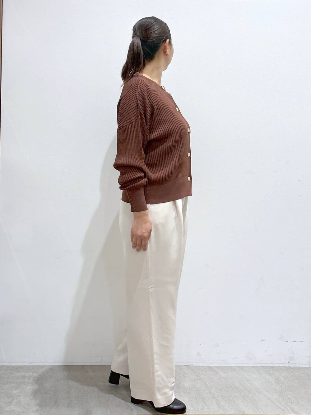 ブラウン系のカーディガン/ボレロ、ブラック系のブーツ、ブラウン系のハンドバッグを着用したレディースの秋コーディネートの5枚目の写真