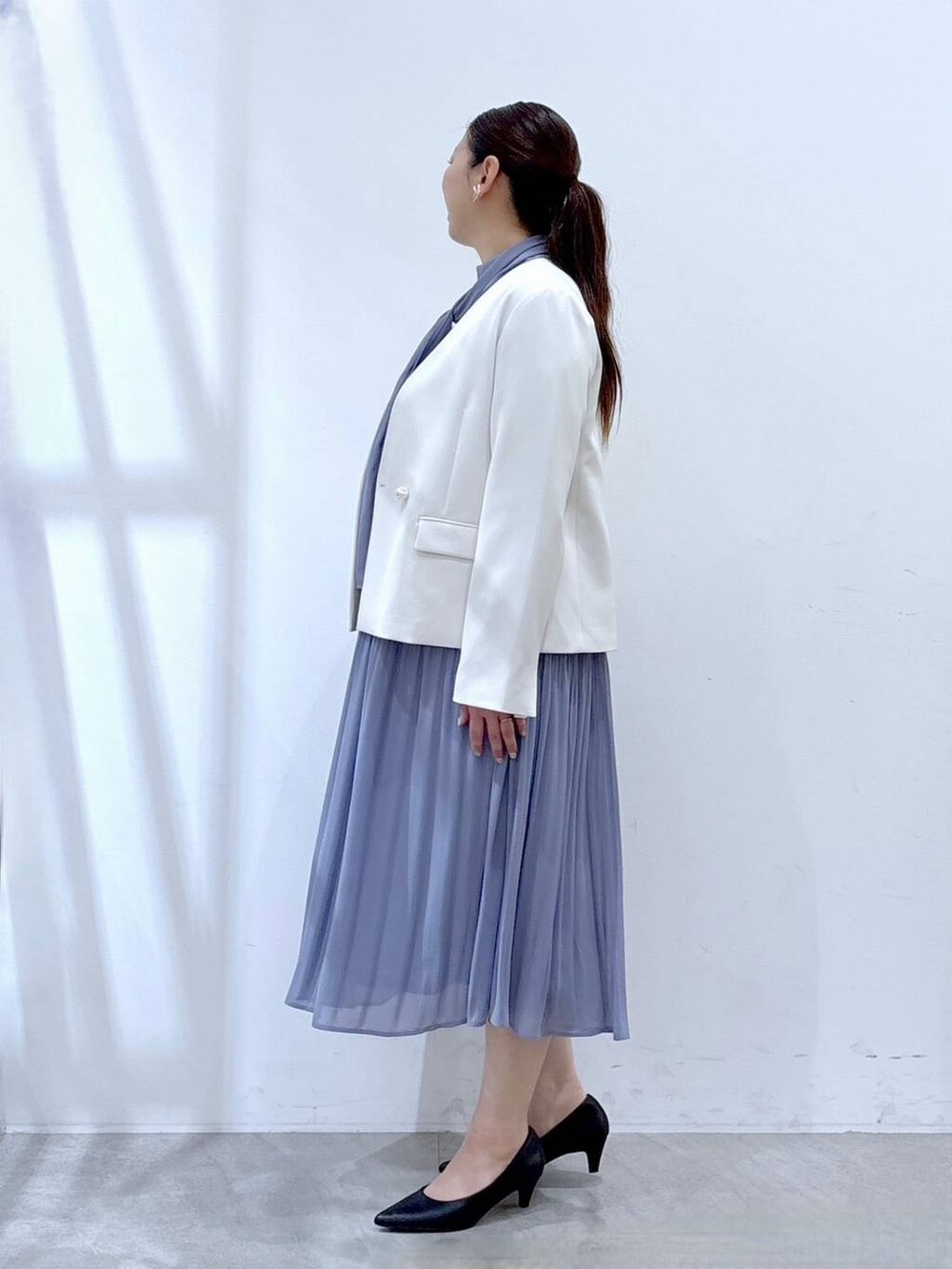 ブラック系のハンドバッグ、ホワイト系のノーカラージャケット、ブルー系のワンピースを着用したレディースの冬コーディネートの3枚目の写真