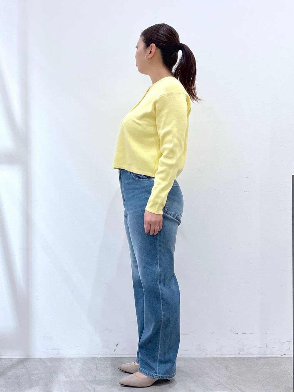 ベージュ系のパンプス、ブルー系のデニムパンツ、イエロー系のカーディガン/ボレロを着用したレディースの冬コーディネートの3枚目の写真