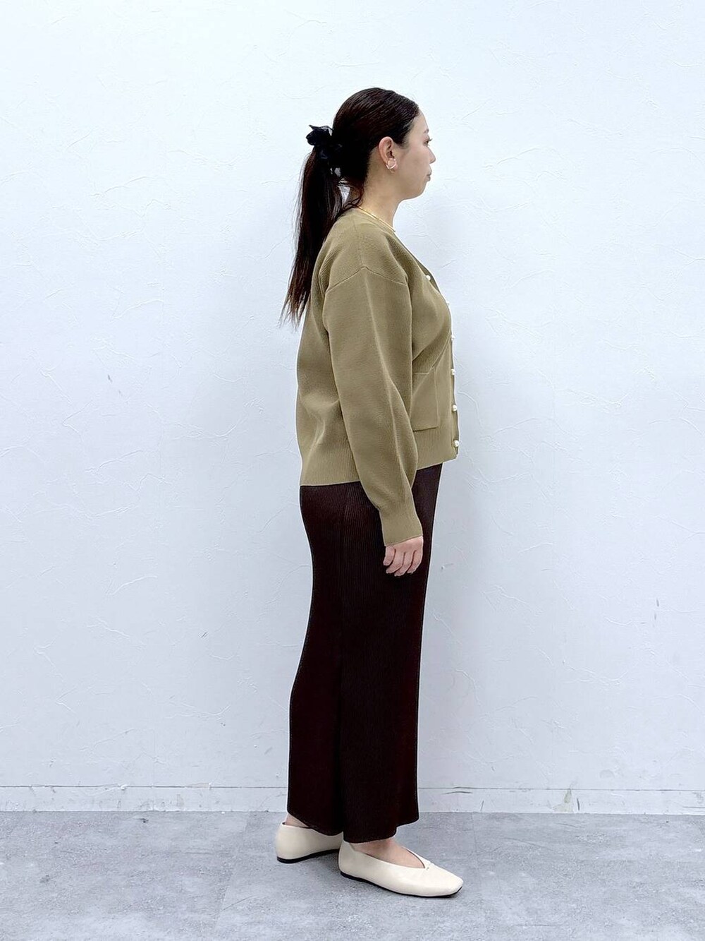 ホワイト系のパンプス、ホワイト系のハンドバッグ、イエロー系のカーディガン/ボレロを着用したレディースの冬コーディネートの5枚目の写真