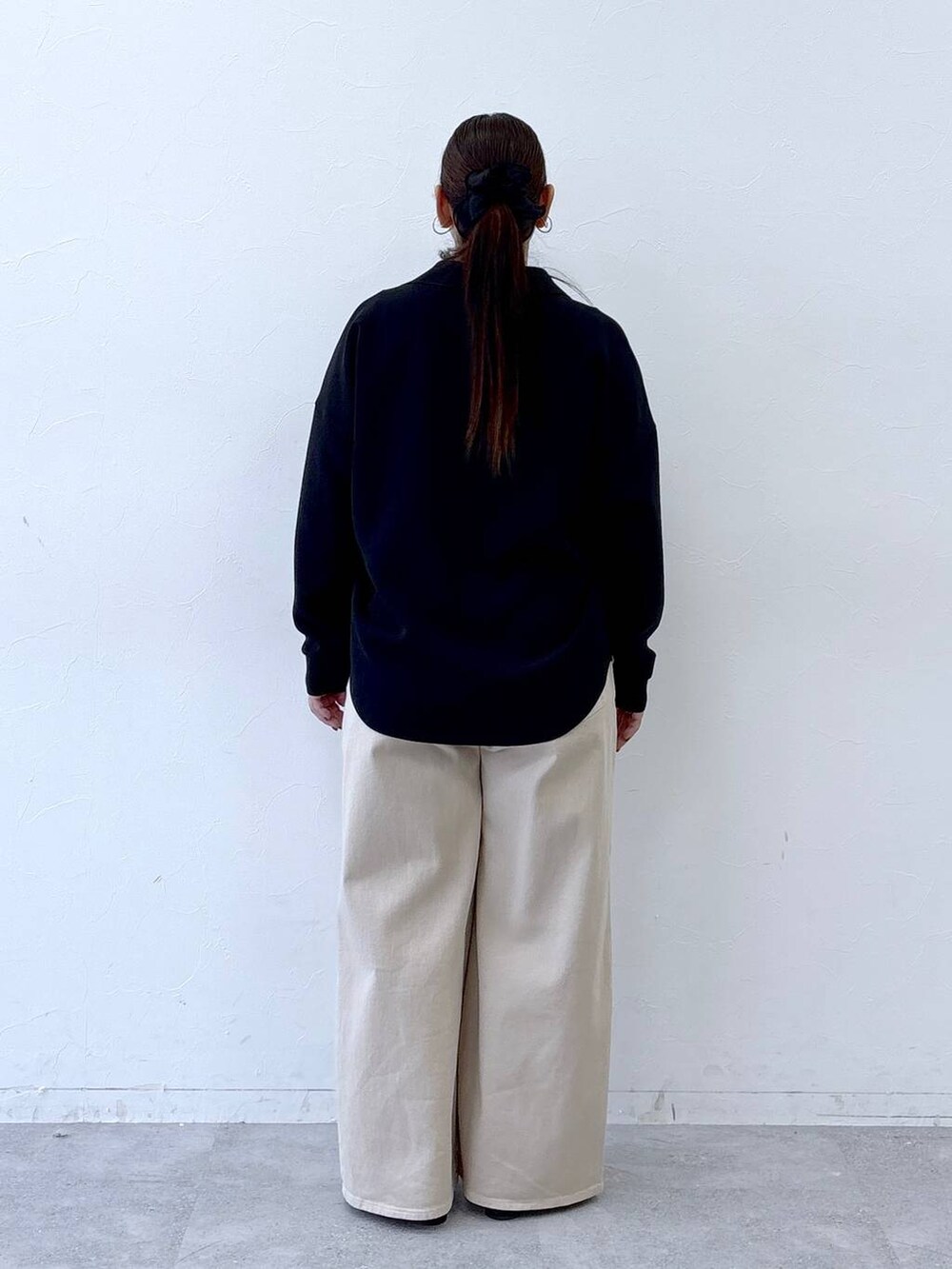 ブラック系のハンドバッグ、ベージュ系のデニムパンツ、ブラック系のパンプスを着用したレディースの冬コーディネートの4枚目の写真