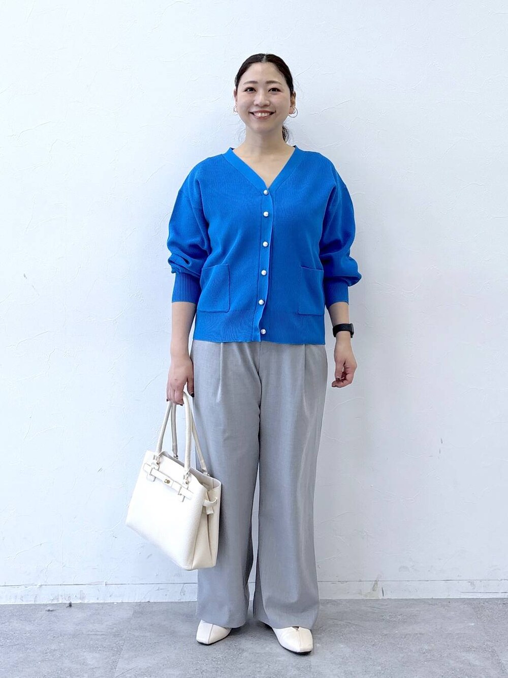 ホワイト系のパンプス、ホワイト系のハンドバッグ、グレー系のその他パンツを着用したレディースの冬コーディネートの2枚目の写真