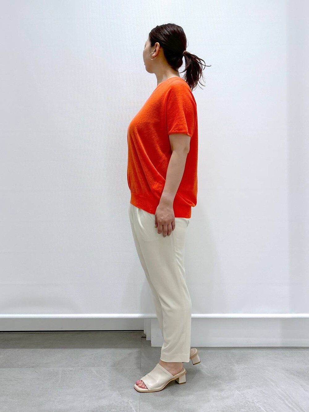 ホワイト系のサンダル、オレンジ系のニット/セーター、ホワイト系のその他パンツを着用したレディースの春コーディネートの2枚目の写真