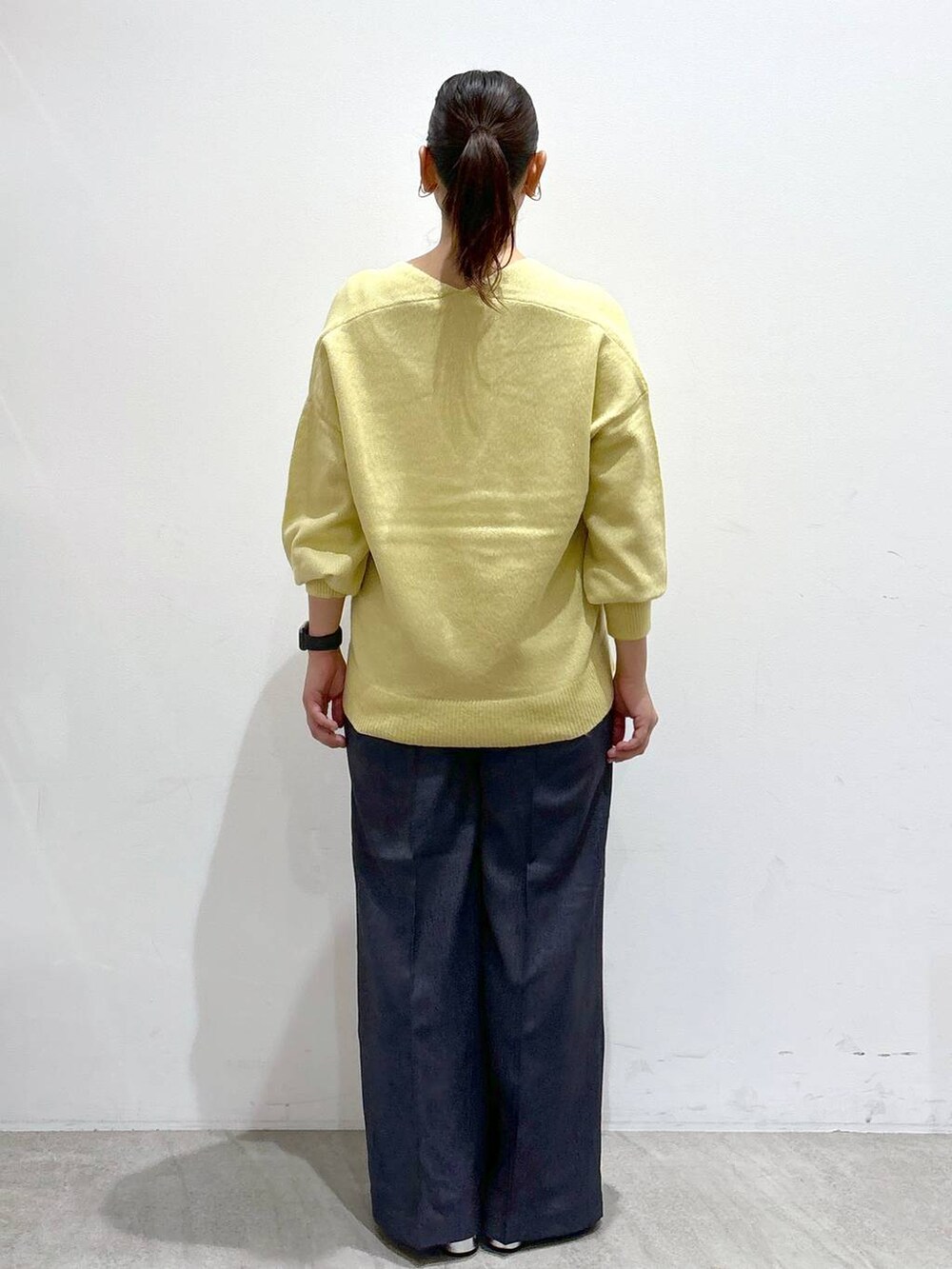 シルバー系のローファー、イエロー系のニット/セーター、ブルー系のデニムパンツを着用したレディースの秋コーディネートの4枚目の写真