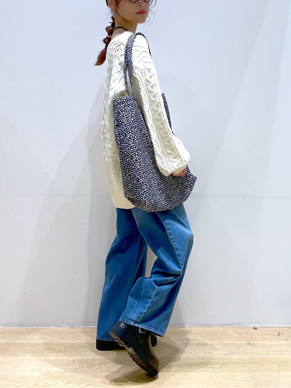 ブルー系のデニムパンツ、ブラック系のブーツ、ホワイト系のニット/セーターを着用したレディースの冬コーディネートの5枚目の写真