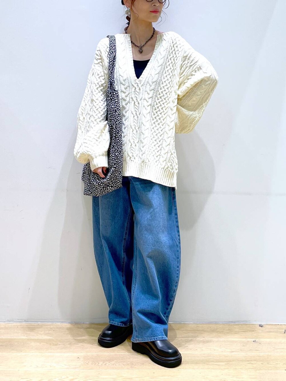 ブルー系のデニムパンツ、ブラック系のブーツ、ホワイト系のニット/セーターを着用したレディースの冬コーディネートの6枚目の写真