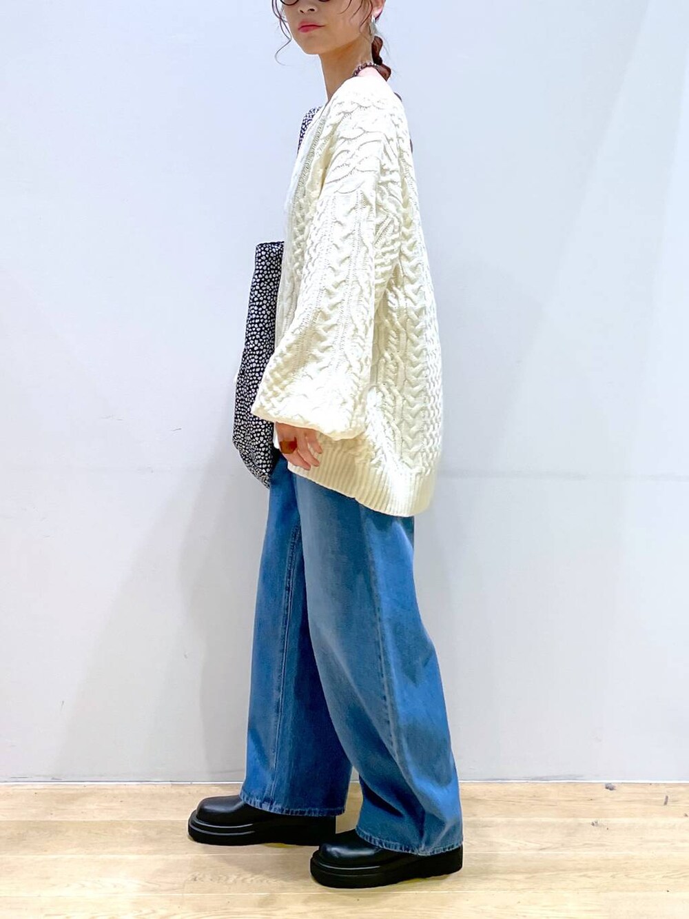 ブルー系のデニムパンツ、ブラック系のブーツ、ホワイト系のニット/セーターを着用したレディースの冬コーディネートの3枚目の写真