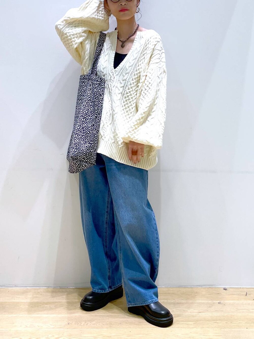 ブルー系のデニムパンツ、ブラック系のブーツ、ホワイト系のニット/セーターを着用したレディースの冬コーディネートの2枚目の写真