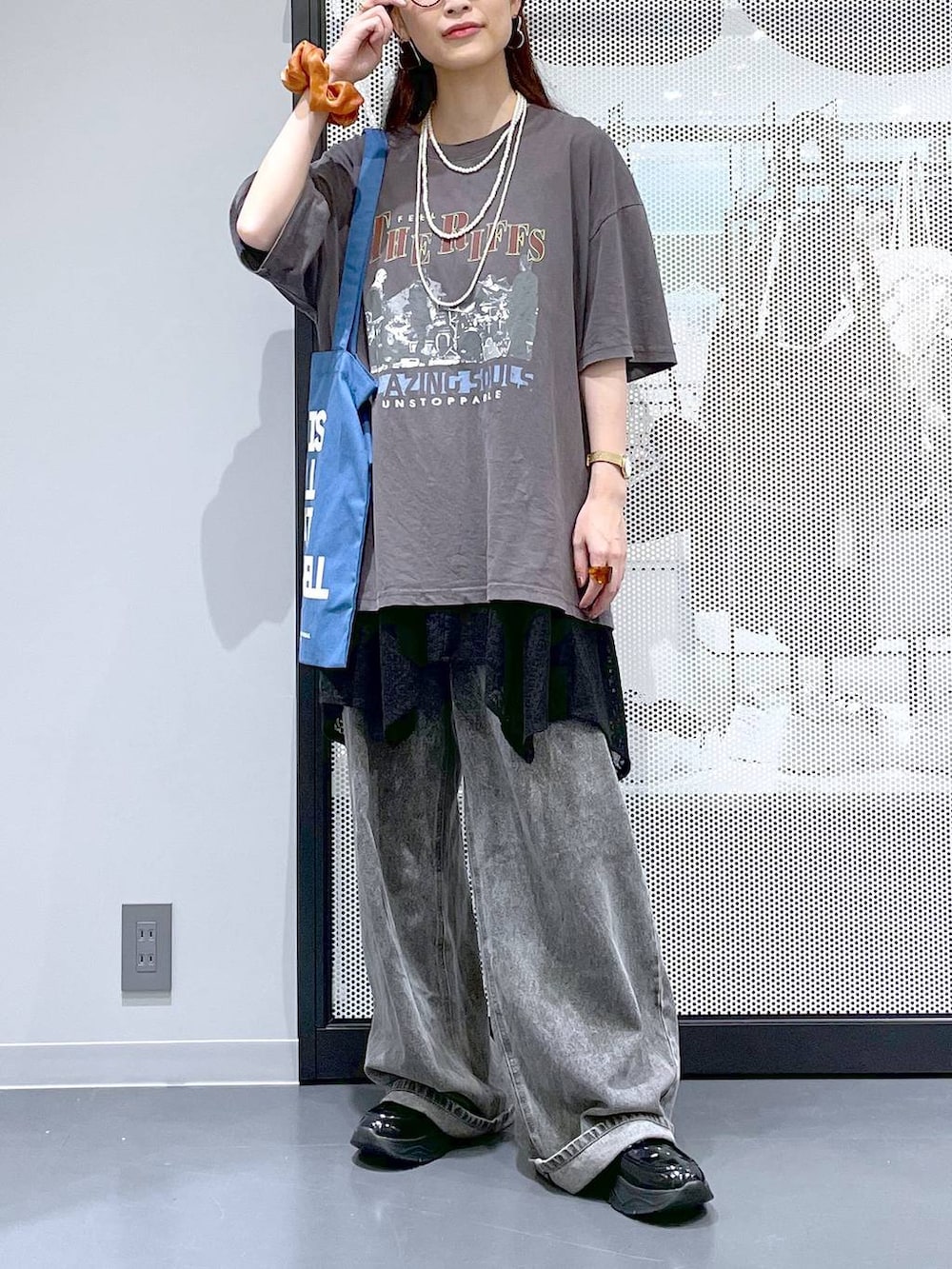 ブラック系のデニムパンツ、ブルー系のトートバッグ、グレー系のTシャツ/カットソーを着用したレディースの夏コーディネートの2枚目の写真