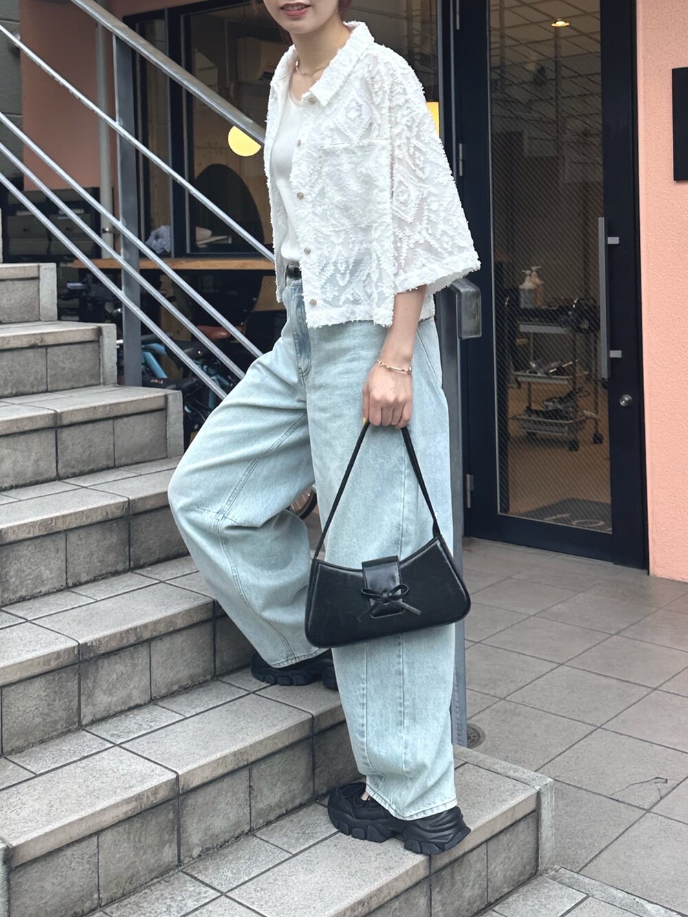 ブルー系のデニムパンツ、ブラック系のサンダル、ホワイト系のシャツ/ブラウスを着用したレディースの夏コーディネートの4枚目の写真