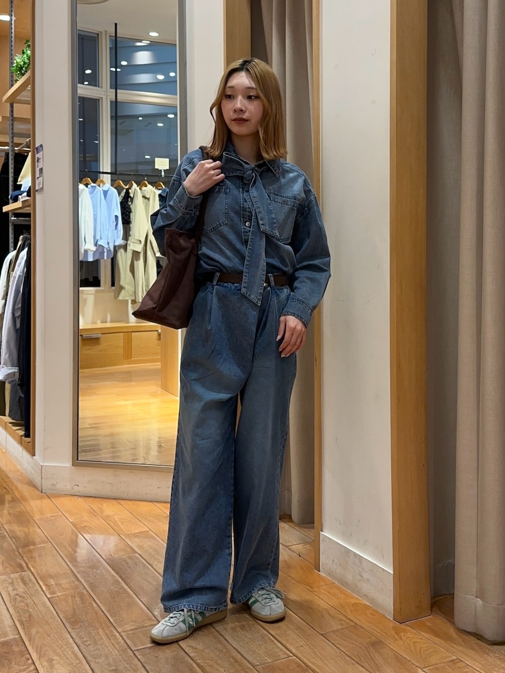 ブルー系のシャツ/ブラウス、ブルー系のデニムパンツ、ブラウン系のトートバッグを着用したレディースの春コーディネートの2枚目の写真