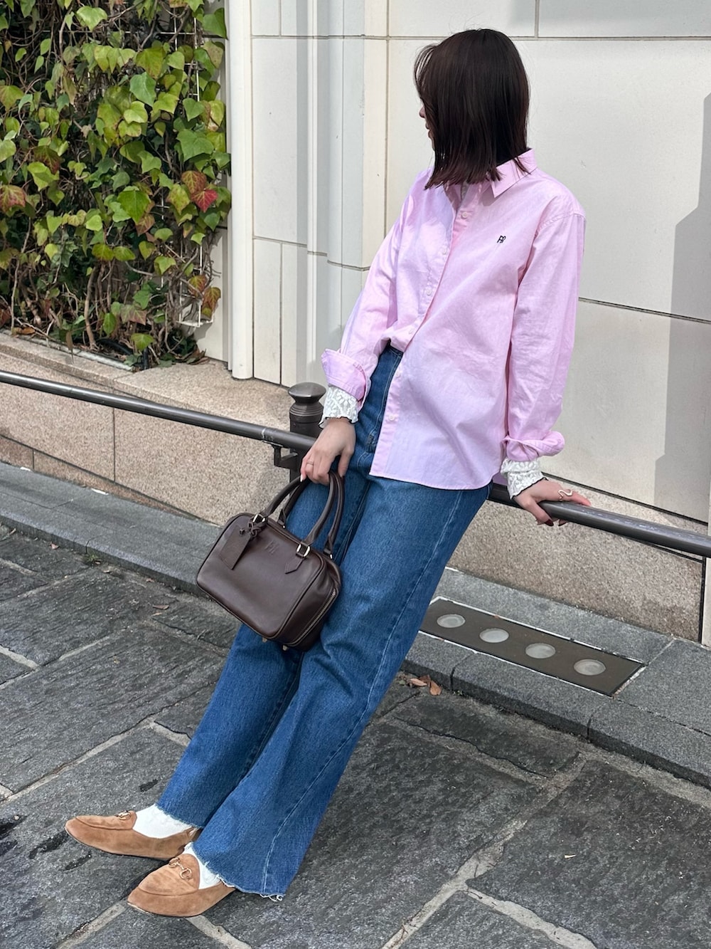 ブルー系のデニムパンツ、ブラウン系のハンドバッグ、ピンク系のシャツ/ブラウスを着用したレディースの冬コーディネートの2枚目の写真