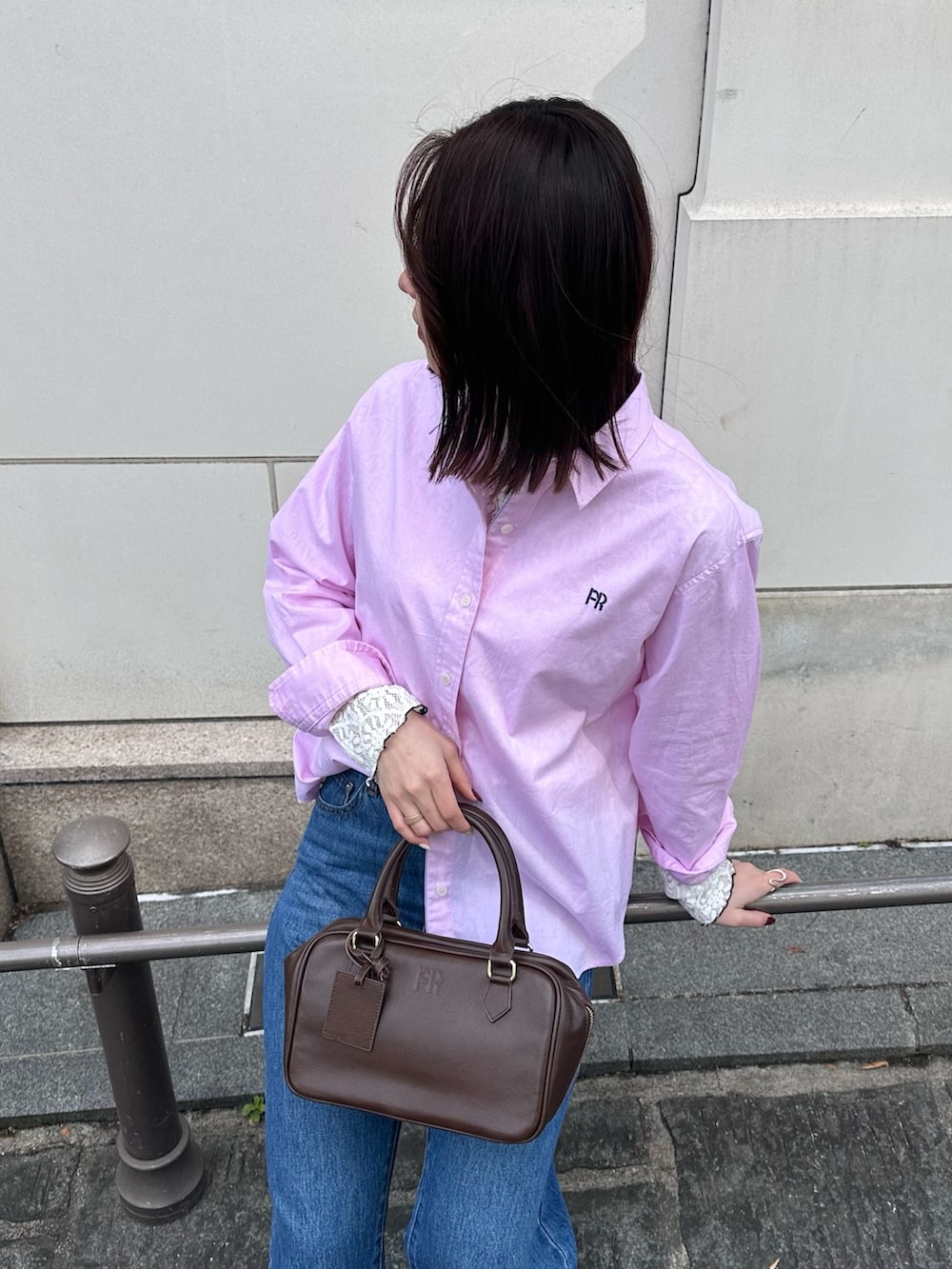 ブルー系のデニムパンツ、ブラウン系のハンドバッグ、ピンク系のシャツ/ブラウスを着用したレディースの冬コーディネートの6枚目の写真