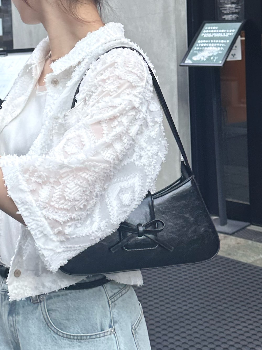 ブルー系のデニムパンツ、ブラック系のサンダル、ホワイト系のシャツ/ブラウスを着用したレディースの夏コーディネートの6枚目の写真