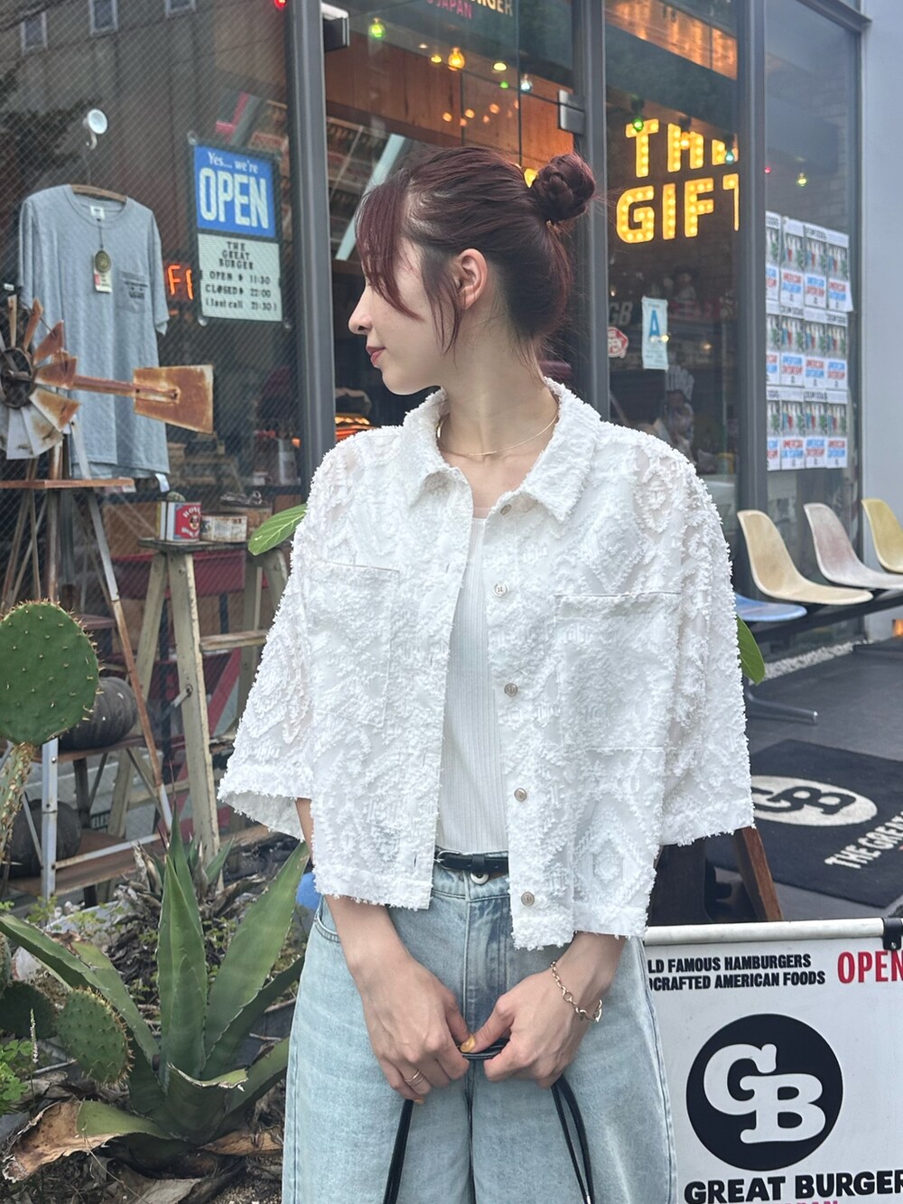 ブルー系のデニムパンツ、ブラック系のサンダル、ホワイト系のシャツ/ブラウスを着用したレディースの夏コーディネートの2枚目の写真