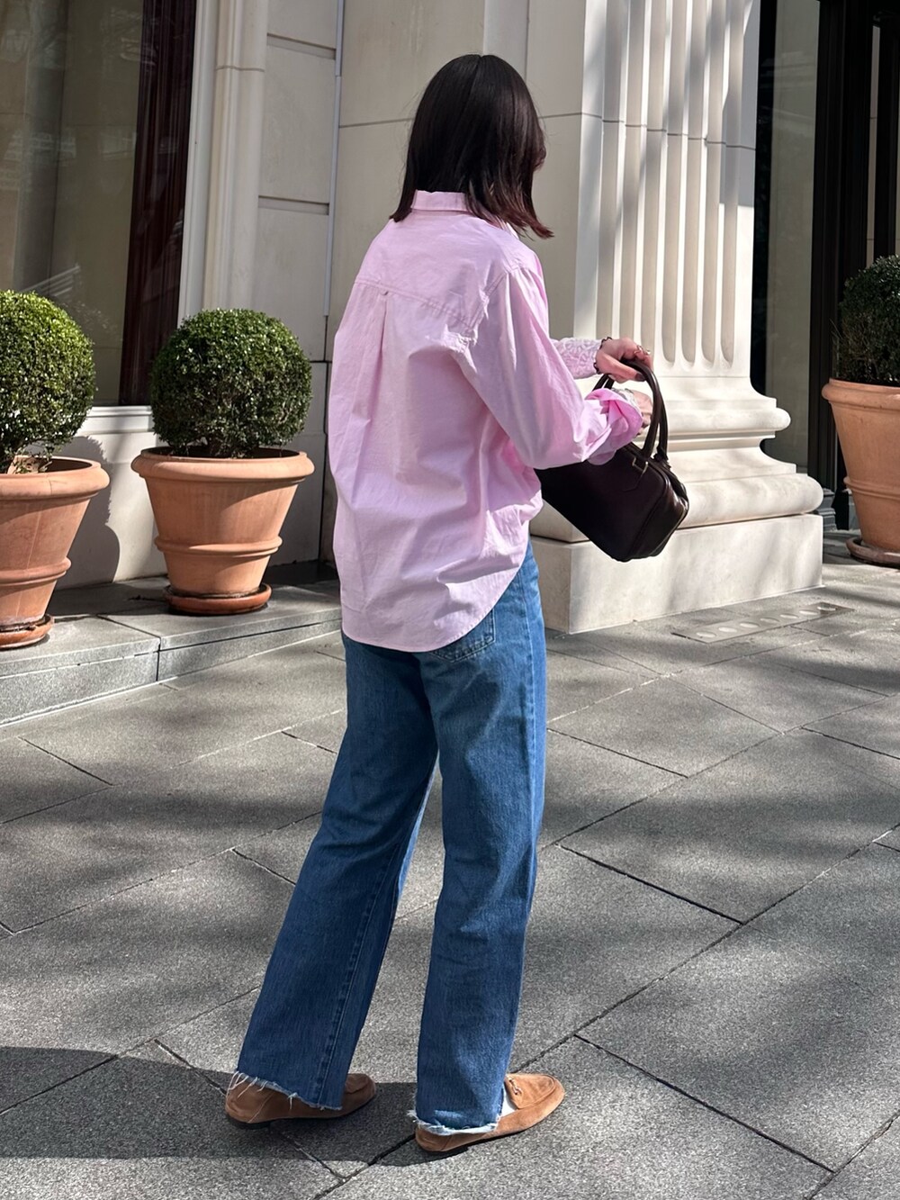 ブルー系のデニムパンツ、ブラウン系のハンドバッグ、ピンク系のシャツ/ブラウスを着用したレディースの冬コーディネートの7枚目の写真