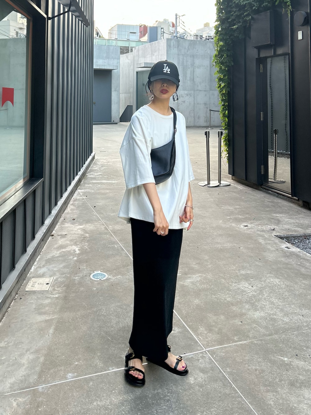 ブラック系のワンピース、ブラック系のショルダーバッグ、ブラック系のキャップを着用したレディースの夏コーディネートの2枚目の写真