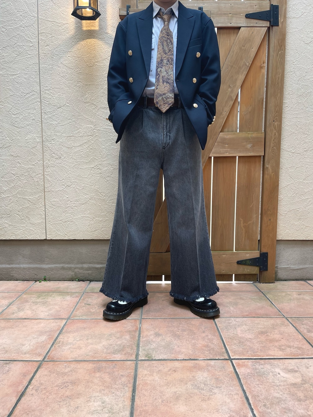 ブルー系のテーラードジャケット、グレー系のデニムパンツ、ゴールド系のネクタイを着用したメンズの春コーディネートの2枚目の写真