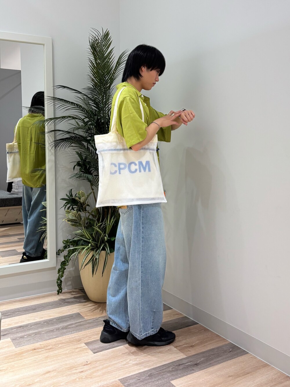 ブルー系のデニムパンツ、グリーン系のシャツ/ブラウス、ホワイト系のトートバッグを着用したメンズの春コーディネートの3枚目の写真