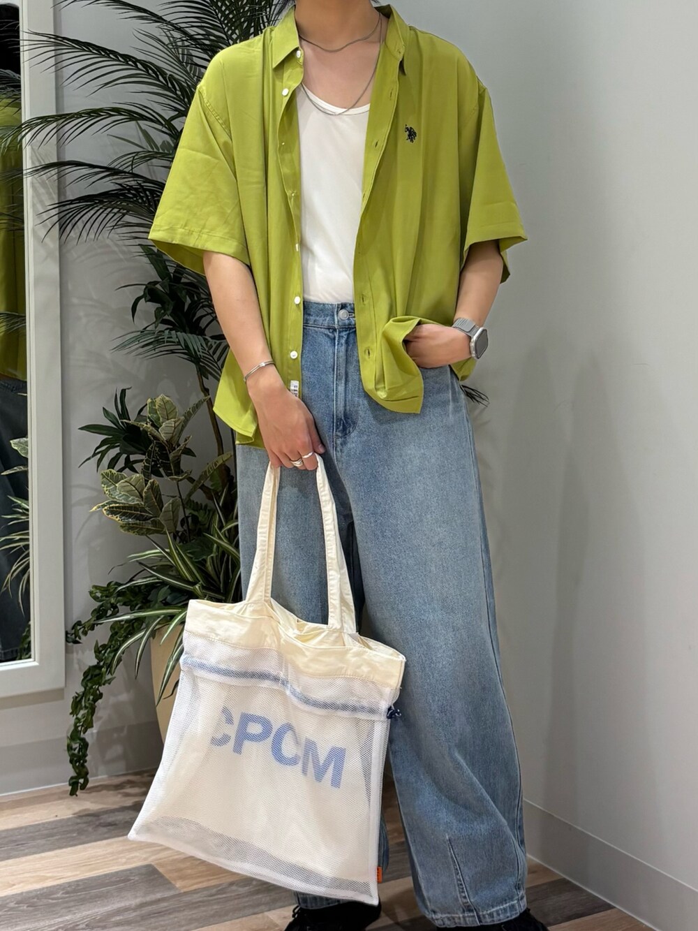 ブルー系のデニムパンツ、グリーン系のシャツ/ブラウス、ホワイト系のトートバッグを着用したメンズの春コーディネートの2枚目の写真