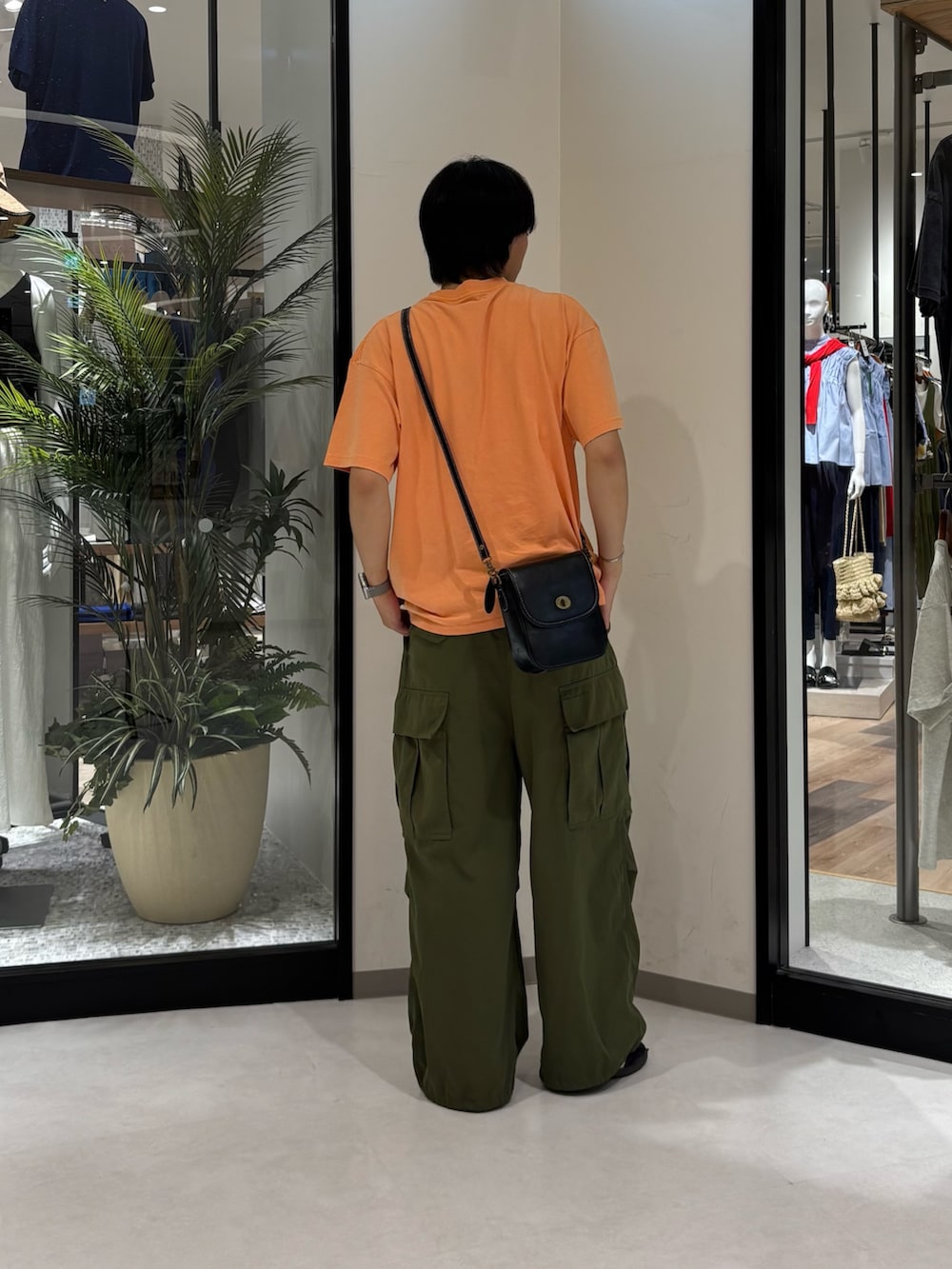グリーン系のカーゴパンツ、オレンジ系のTシャツ/カットソー、ブラック系のショルダーバッグを着用したメンズの夏コーディネートの3枚目の写真