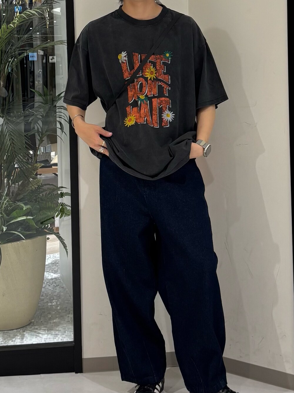 ブルー系のデニムパンツ、ブラック系のTシャツ/カットソー、オレンジ系のショルダーバッグを着用したメンズの夏コーディネートの2枚目の写真