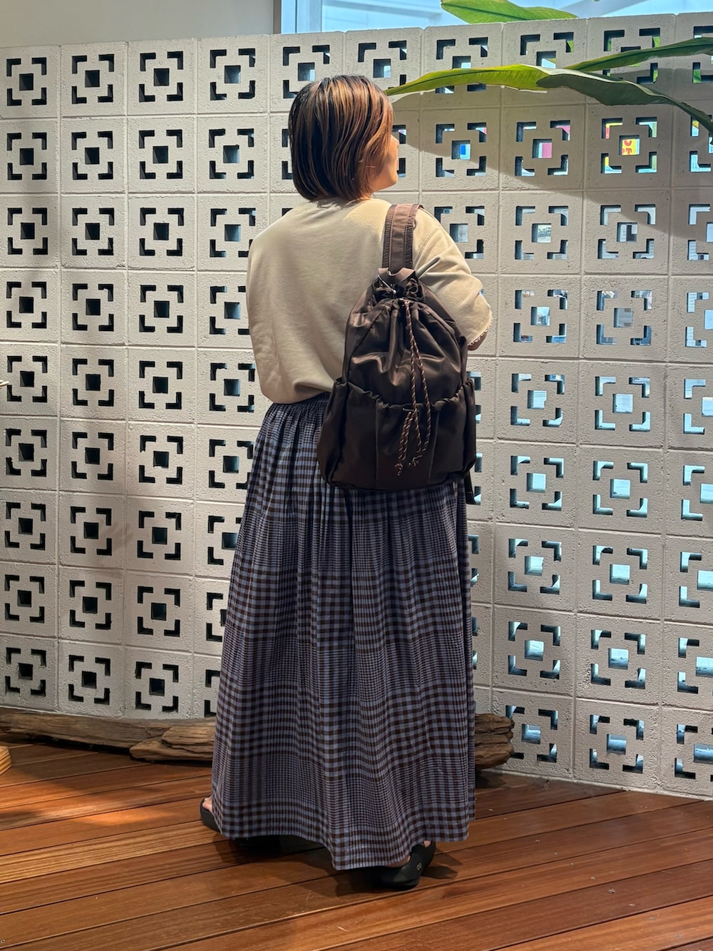 ブラウン系のスカート、ベージュ系のTシャツ/カットソー、ブラック系のサンダルを着用したレディースの夏コーディネートの2枚目の写真